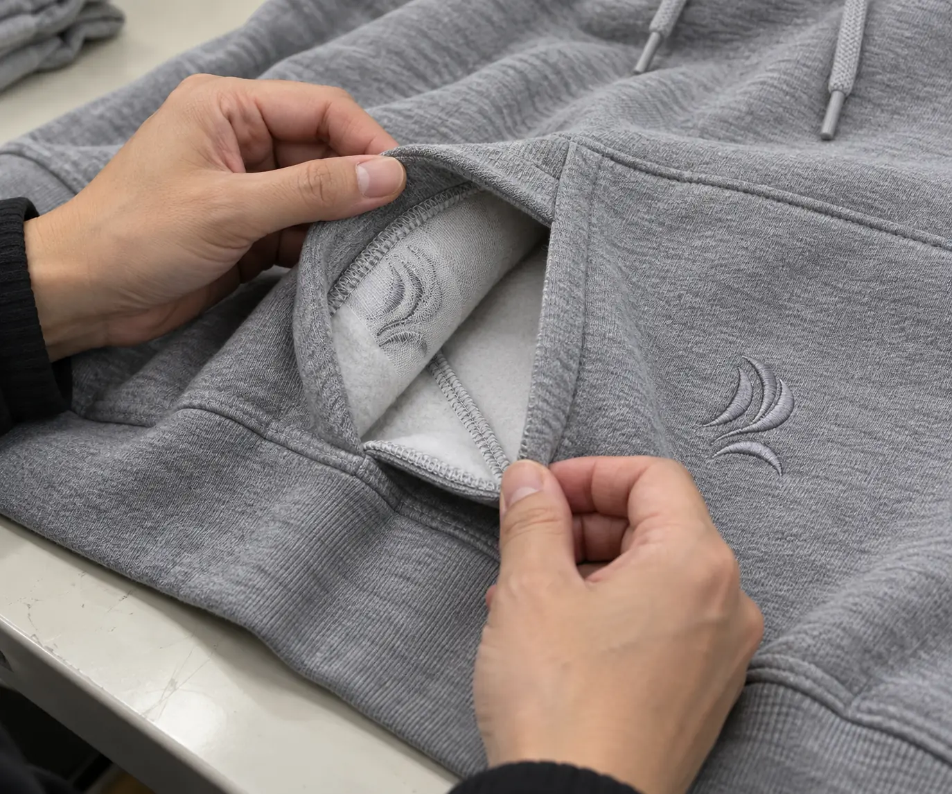 Inspector checking the inside finish and opening of a decorated hoodie pocket