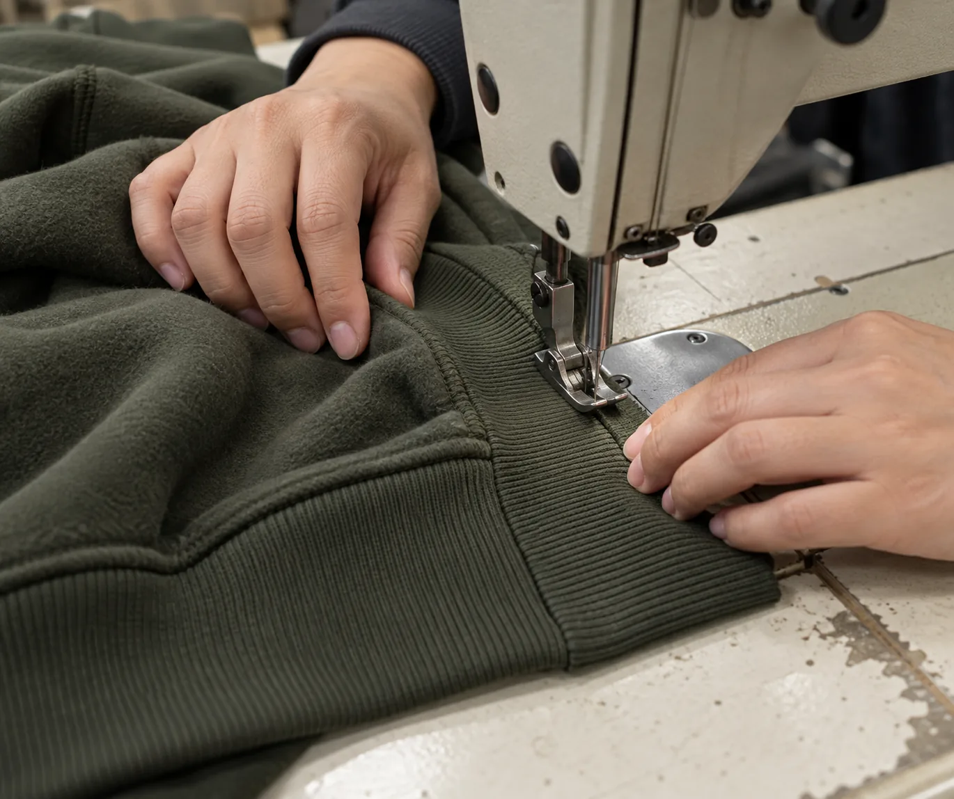 Sewing operator joining rib waistband to a heavyweight hoodie body