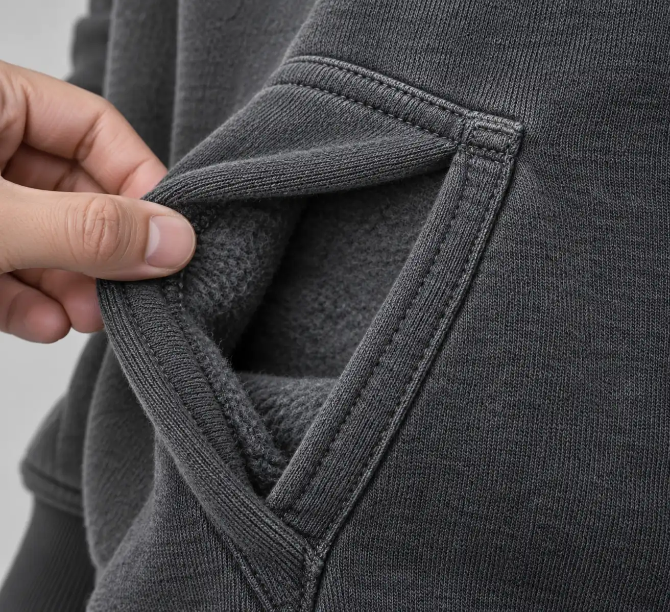 Close view of a hoodie pocket opening and its stitched reinforcement