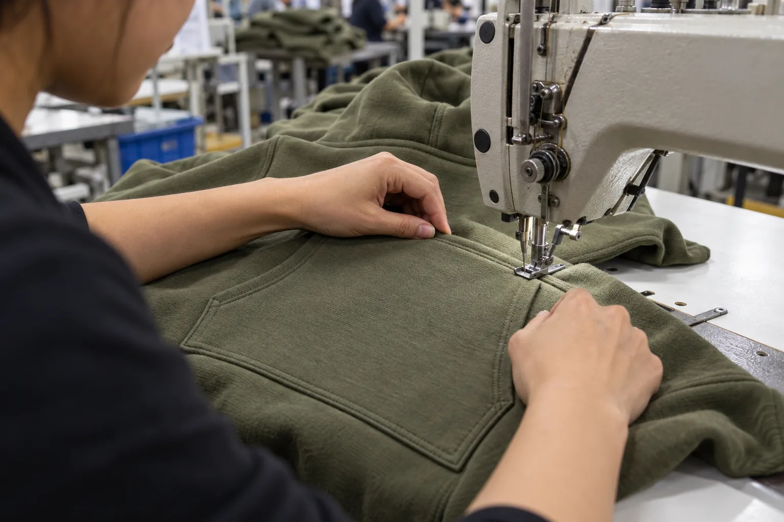 Sewing operator positioning a pocket panel onto a hoodie front