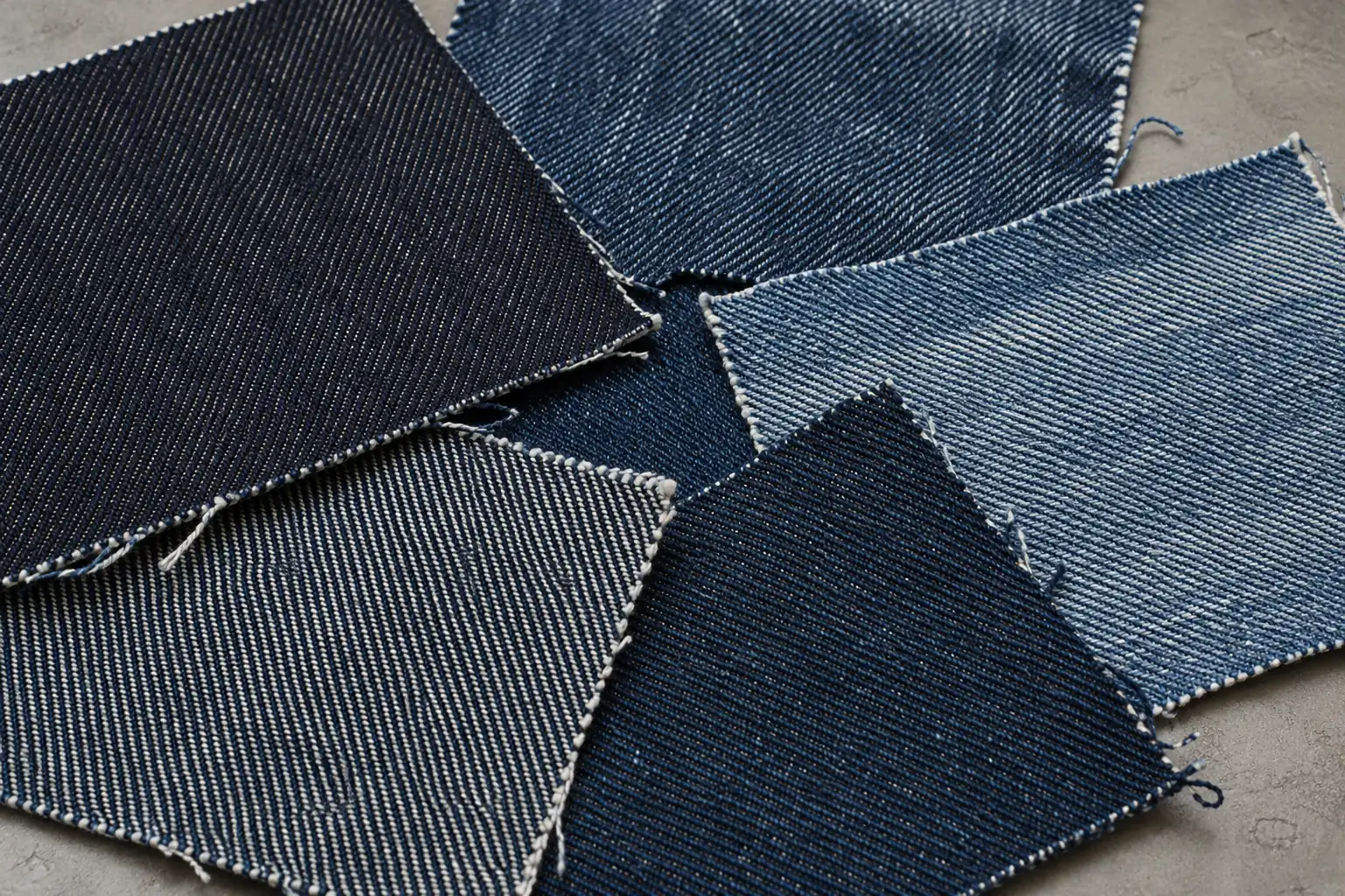Indigo denim swatches with different twills and wash responses on a fabric inspection table