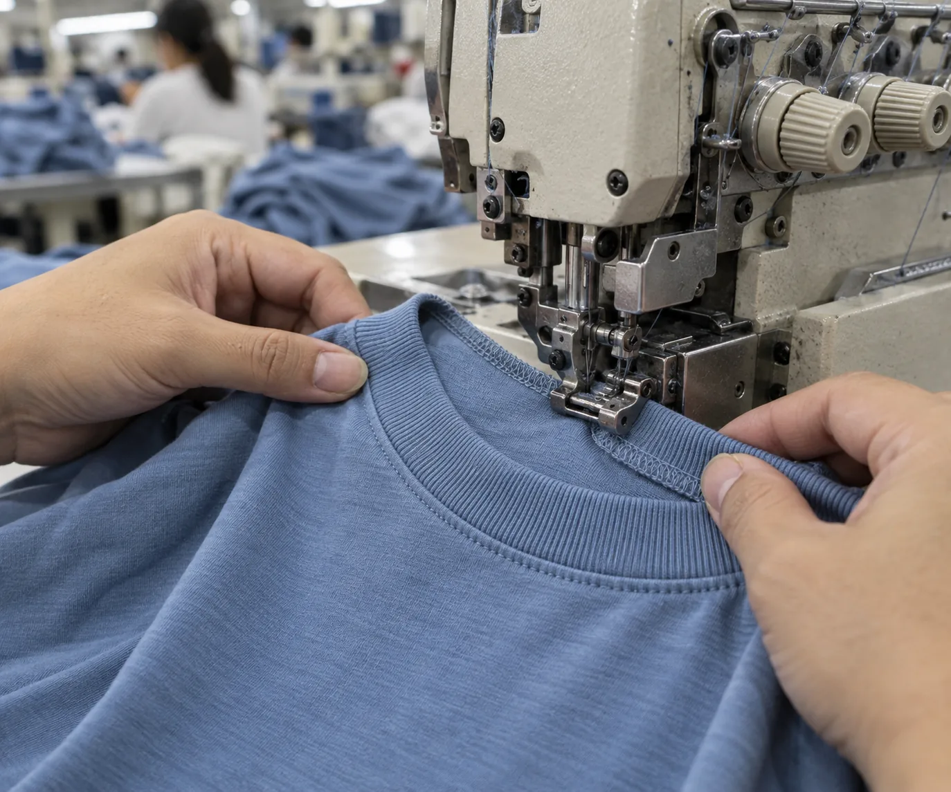 Sewing operator attaching a rib neckband to a plain jersey T-shirt with an overlock machine