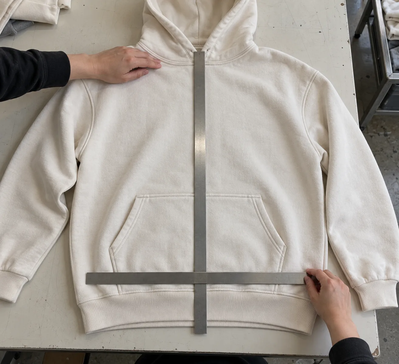 Hoodie sample laid flat with measuring tools aligned around its kangaroo pocket