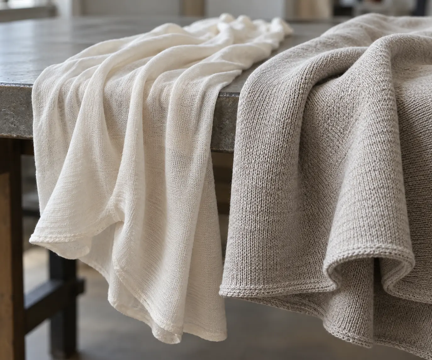 Light and heavyweight cotton jersey swatches draped over the edge of a fabric inspection table