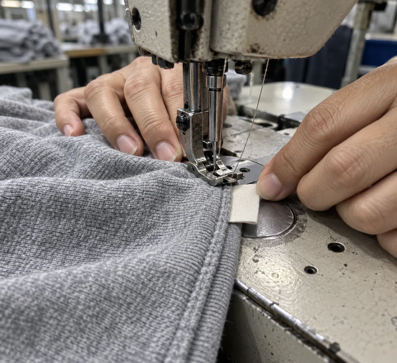 Sewing operator attaching a label into a garment seam