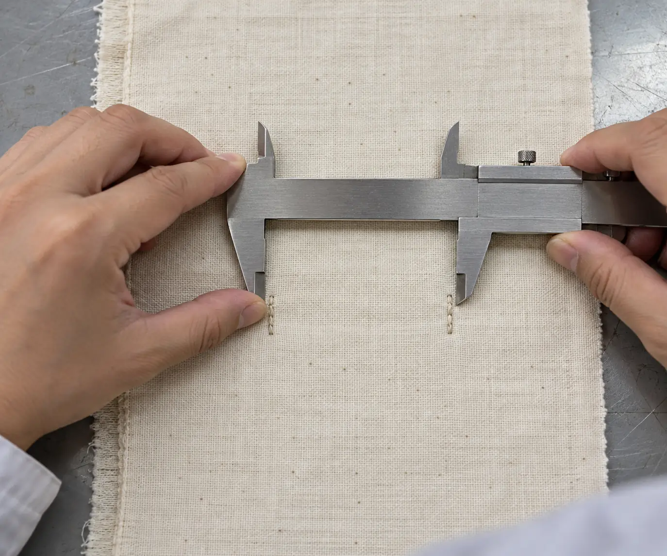 Technician measuring marked reference distances on a fabric specimen